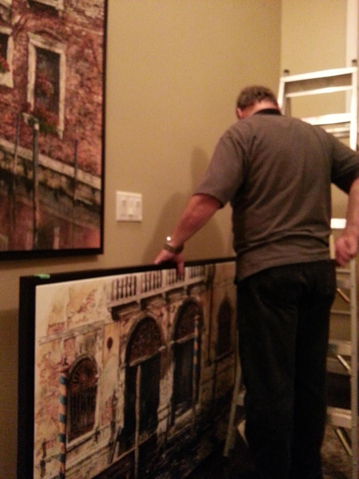Alex Krajewski installs Venice over sized framed canvas at customers' home
